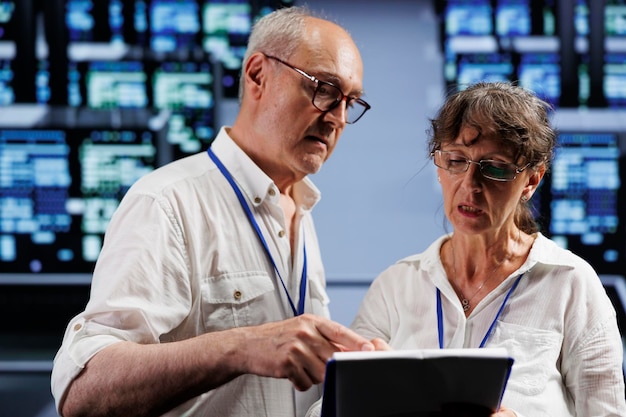 senior engineers monitoring data center rigs optimizing them for data processing requirements of ai applications experienced technicians working in server hub used for machine learning