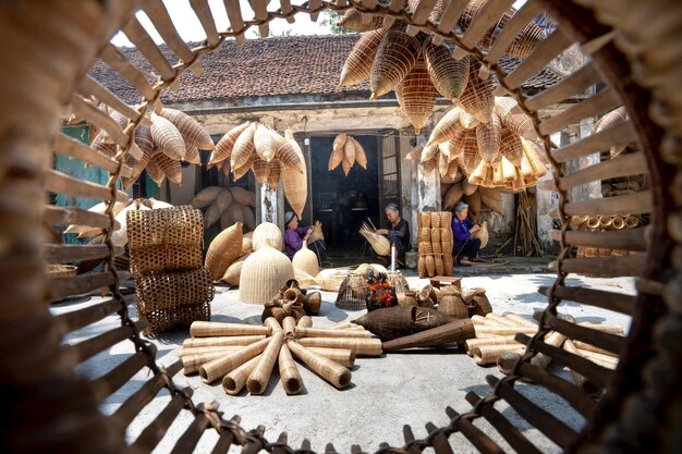 Photo senior ethnic women near shabby residential building and many different timber fish traps in dayligh