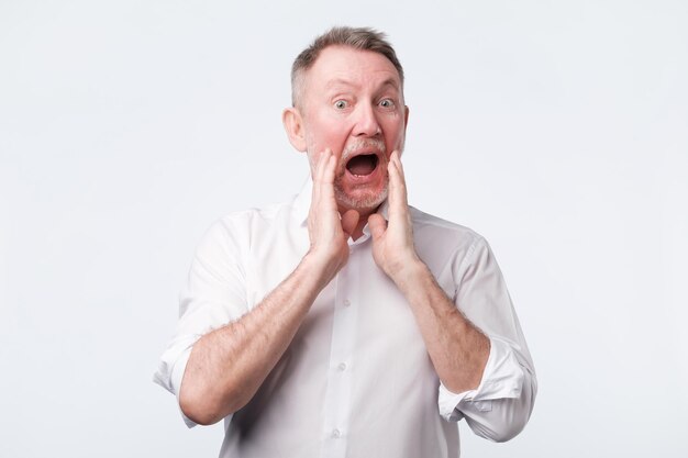 Senior european man in white shirt shout something