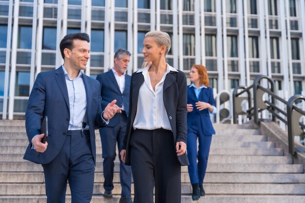 Senior executives discuss strategy while descending stairs in commercial building