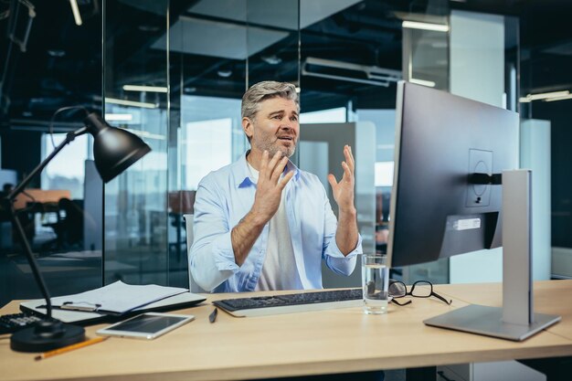 Senior and experienced businessman looks frustrated at the monitor complains about poor performance man at work