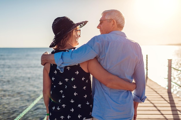 Senior family couple walking on pier by Red sea Retired people enjoying vacation in tropical Egypt enjoying landscape Back view