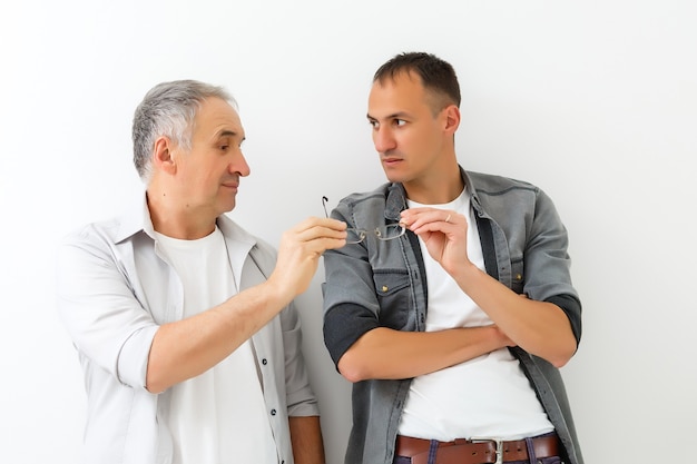 Senior father with adult son talking, isolated white wall.