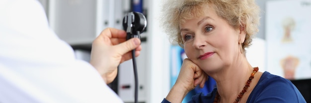 La donna anziana su appuntamento misura la pressione sanguigna con l'attrezzatura