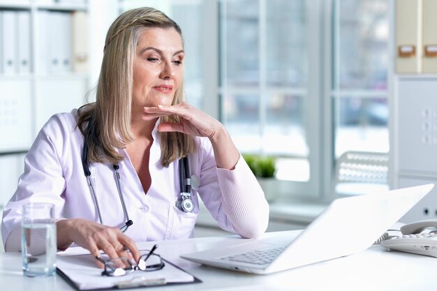 Senior female doctor working at her cabinet