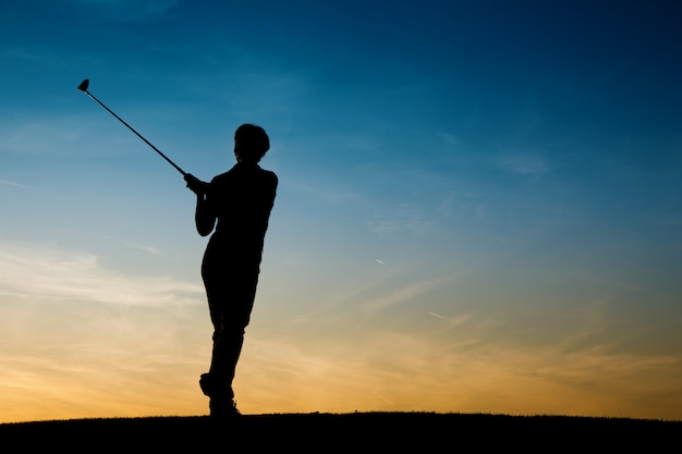 Senior female golf player at sunset