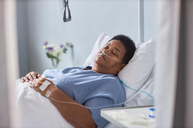 Senior female patient sleeping on bed in hospital room