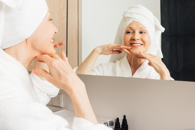 Senior female with a towel wrapped around her head enjoying her morning routine in the bathroomx9xA