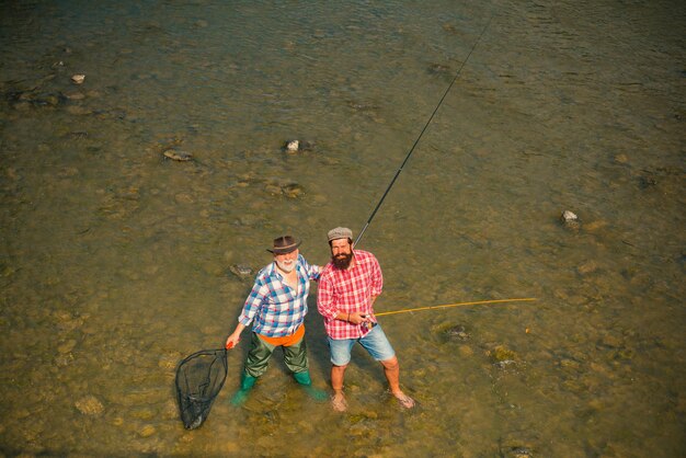 写真 スーツを着た上級漁師とひげを生やしたカジュアルな男性が釣り竿の水面で釣りをしています