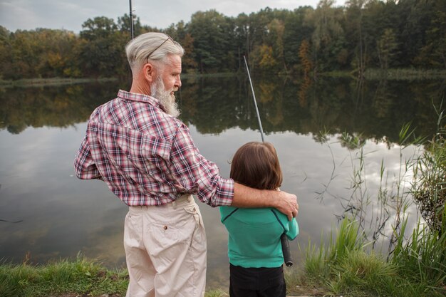 senior fisherman teaching his grandson to fish