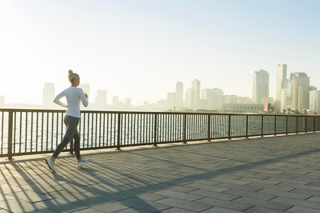 Senior fitness woman jogging on seafront promenade in sunshine morning Healthy lifestyle sport active life in city