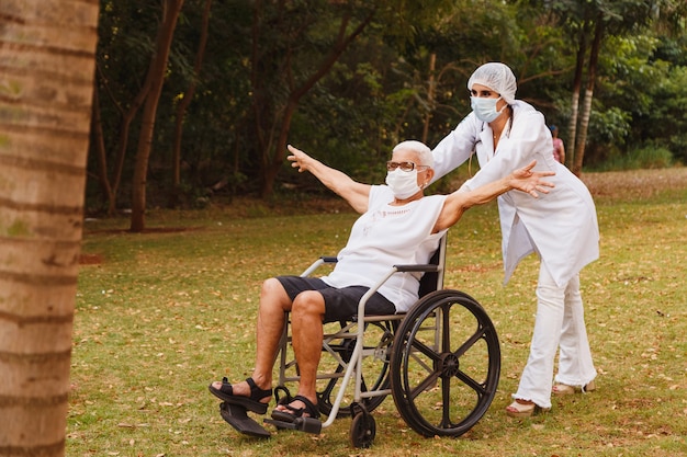 Senior gehandicapte vrouw met verzorger in de tuin van het verpleeghuis