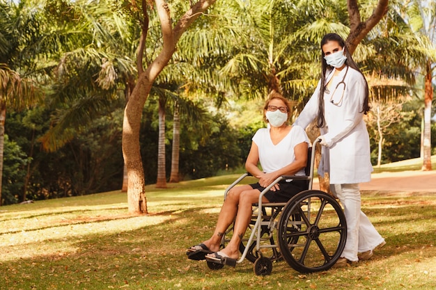 Senior gehandicapte vrouw met verzorger in de tuin van het verpleeghuis