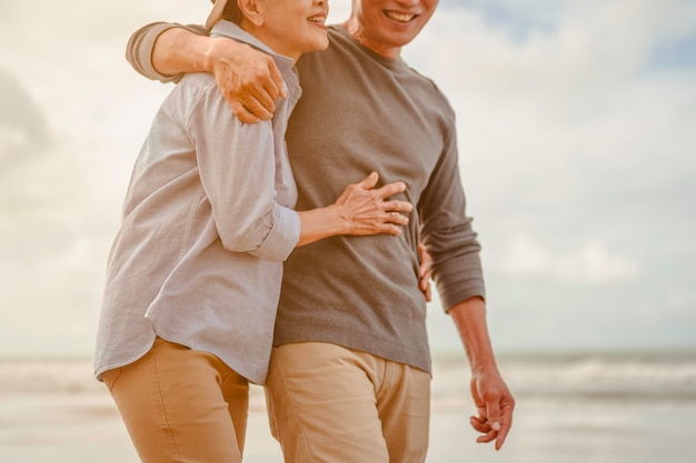 Senior geliefden omhelzen elkaar in de zonsondergang op het strand Plan een levensverzekering met een gelukkig pensioenconcept.