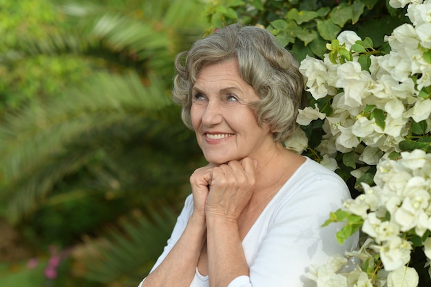 Senior gelukkig lachende vrouw met witte bloemen