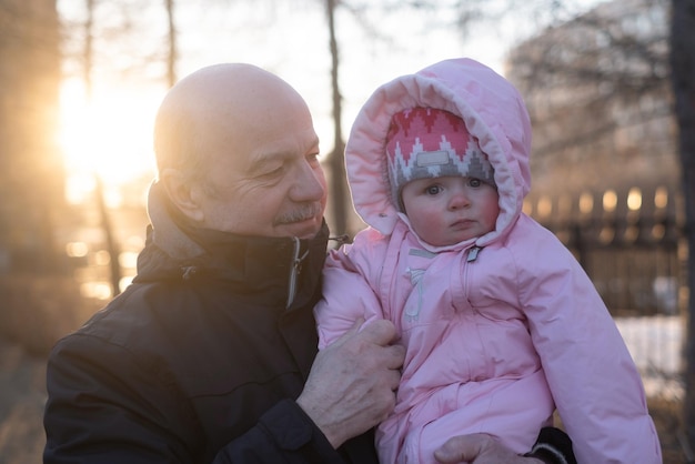 Senior grandfather holding his baby granddaughter smiling