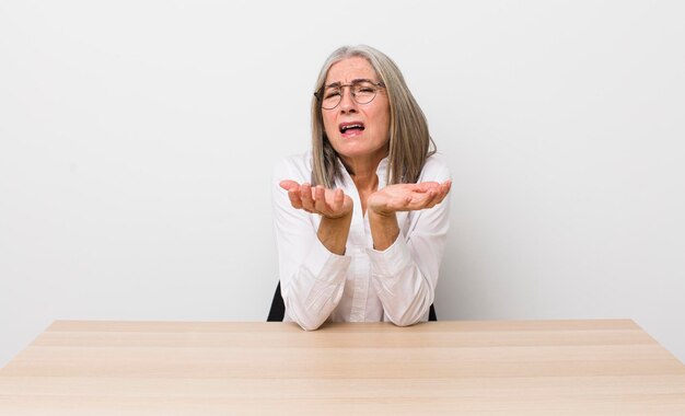 Senior gray hair woman looking desperate frustrated and stressed desk and business concept