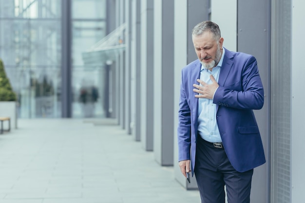 Senior grayhaired banker boss sick outside office building banker has severe chest pain heart aches