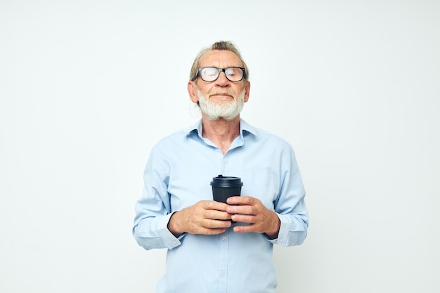 Senior greyhaired man gestures with his hands a glass of drink light background