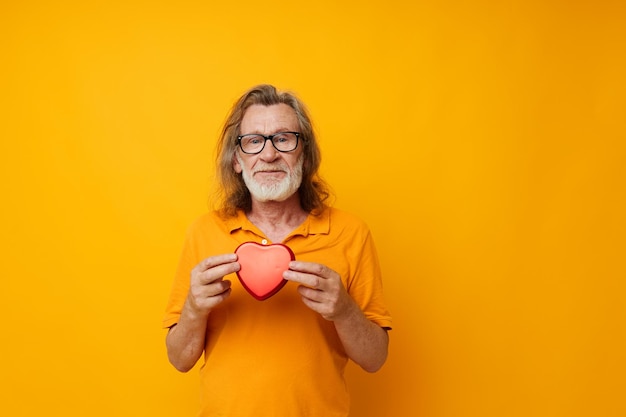 Senior greyhaired man red heart gift emotions yellow glasses cropped view