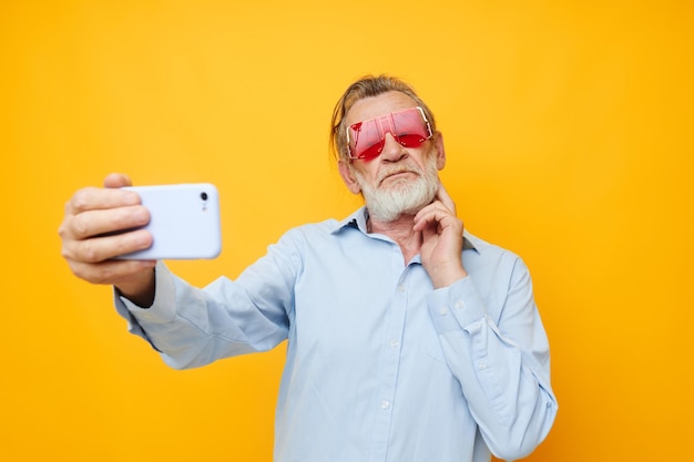Senior grijsharige man blauwe shirts met bril neemt een selfie bijgesneden weergave