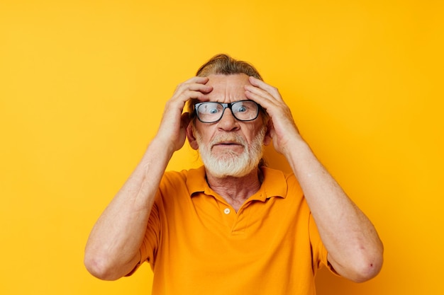 Senior grijsharige man poseren gele tshirt bril gele achtergrond