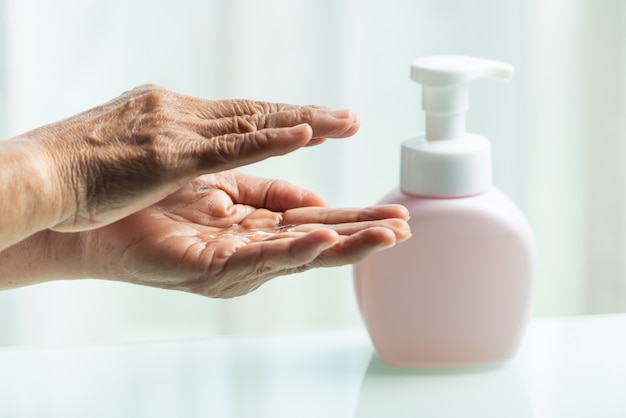 senior hand apply alcohol gel or anti bacteria soap to make cleaning 
