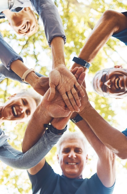 Senior handen samen en ondersteuning met solidariteit outdoor en groepsdiversiteit met teambuilding in de natuur vertrouw op respect en missie met volwassen gemeenschap hand stack lage hoek en samenwerking