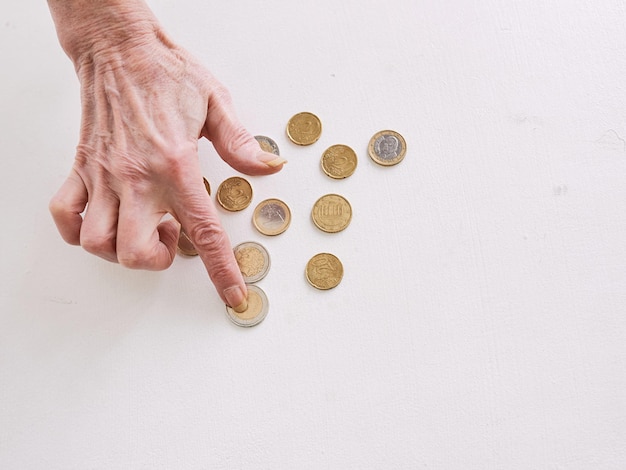 テーブルの貧困危機預金不況の概念でユーロ硬貨を数えるシニアの手
