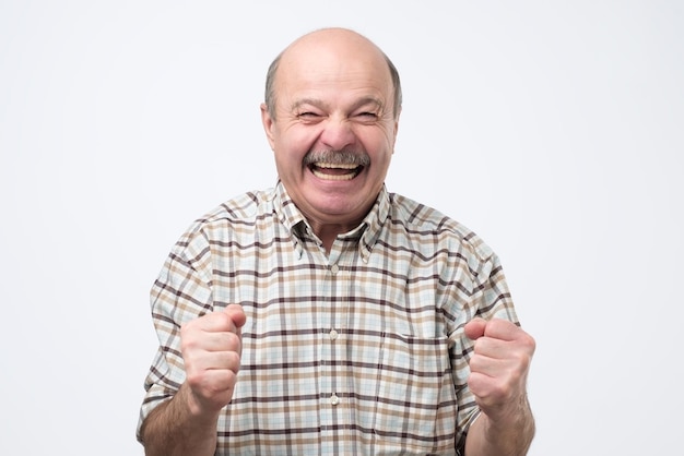 Senior handsome man laughing and looking at camera with a big grin