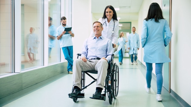 Senior handsome man in a wheelchair is moving in the hospital with help of medical special staff