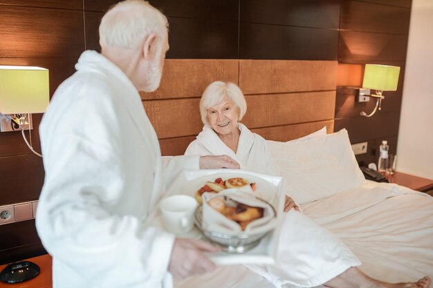 A senior happy couple enjoying breakfast while staying in bed