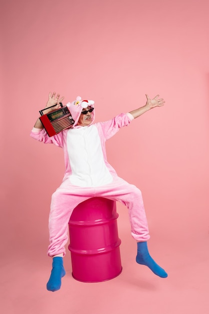 Senior hipster man in stijlvolle roze kleding geïsoleerd op roze achtergrond tech en vrolijk