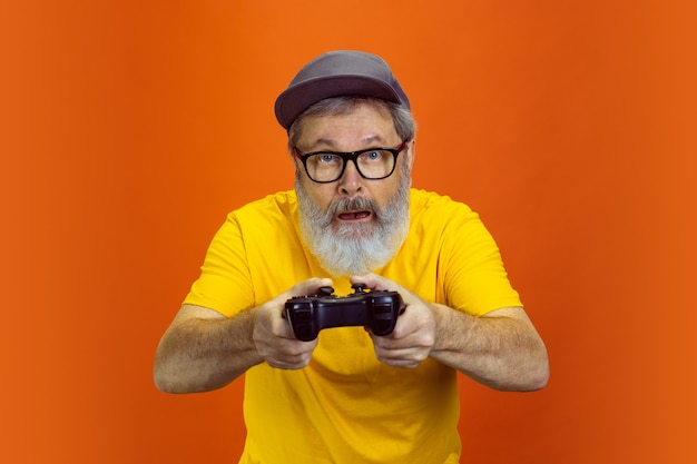 Senior hipster man met apparaten, gadgets op oranje achtergrond