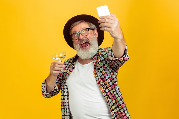 Senior hipster man wearing eyeglasses posing on yellow background