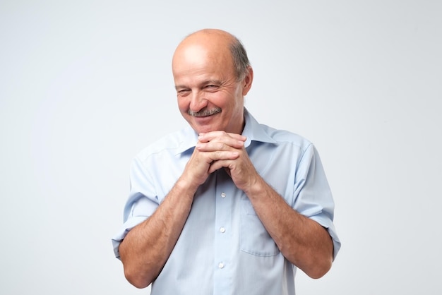 L'uomo ispanico senior che guarda con curiosità esamina la macchina fotografica