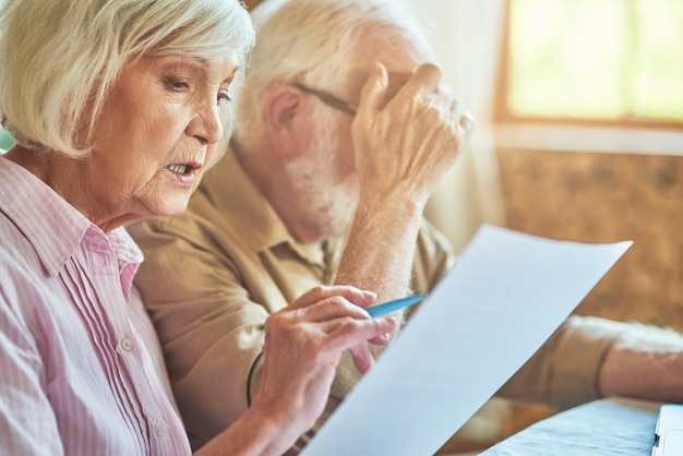 Senior husband and wife analyzing finance papers at home