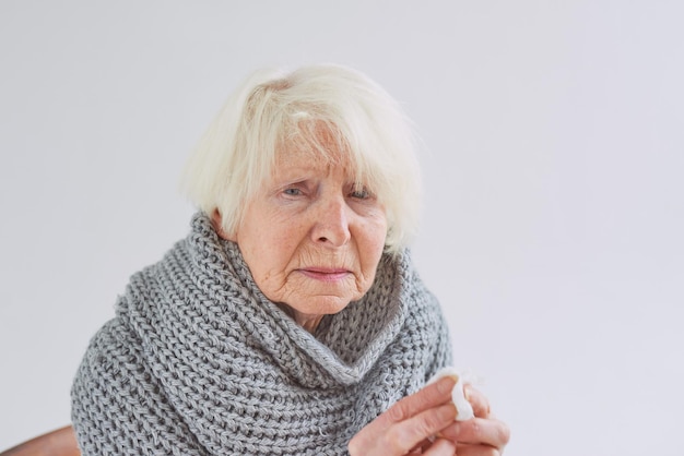 Senior ill woman in scarf freezing cold at home Health care crisis oldness concept