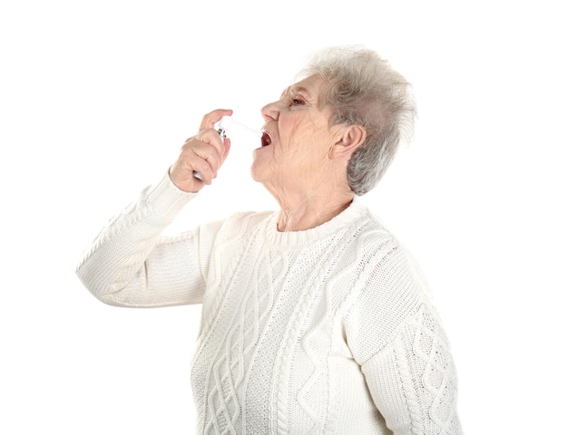 Senior donna malata utilizzando spray, isolato su bianco. concetto di allergia
