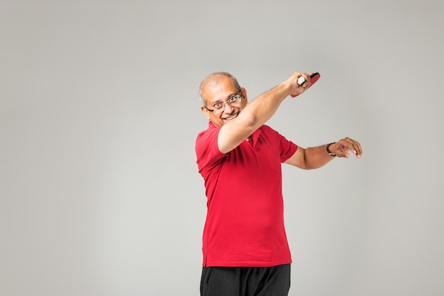 Senior indian asian healthy sportsman playing individual sport or gymming , isolated on plain background