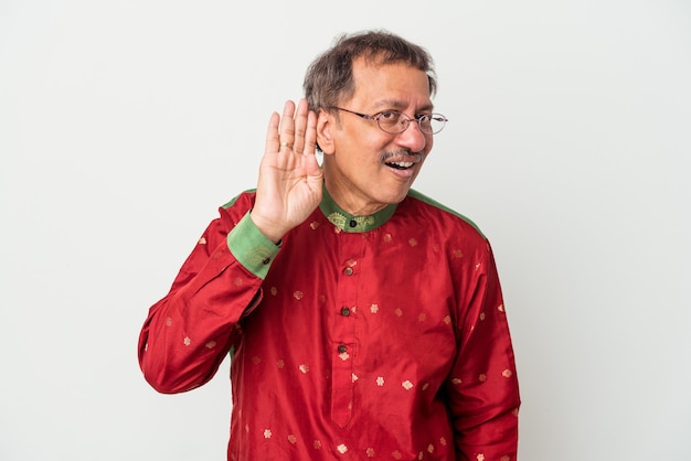 Photo senior indian man wearing a indian costume isolated on white background trying to listening a gossip.