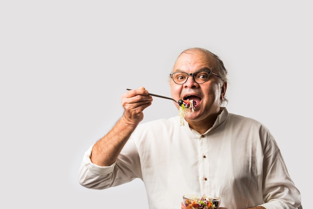 Senior Indiase Aziatische man die verse groene salade eet. Rijpe mannelijke man met gezonde snack, gezondheidszorg, dieetconcept