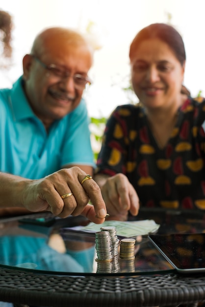 Senior indiase aziatische paar schikken of uitzetten van munten stapel op een rij, selectieve focus