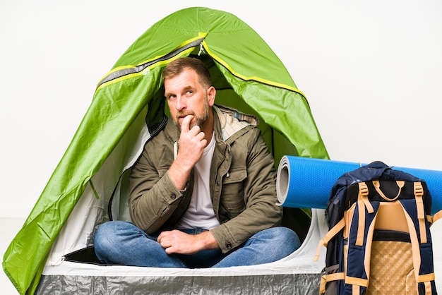 Senior all'interno di una tenda isolata su sfondo bianco rilassato pensando a qualcosa guardando uno spazio di copia.