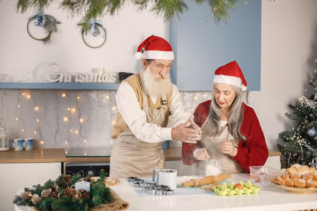 Senior koppel in rode kerstmutsen koken in de keuken