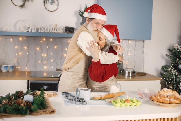 Senior koppel in rode kerstmutsen koken in de keuken