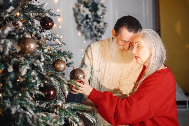 Senior koppel knuffelen en versieren kerstboom samen