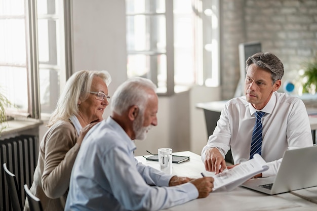 Senior koppel ondertekent een contract tijdens een ontmoeting met bankmanager focus ligt op manager