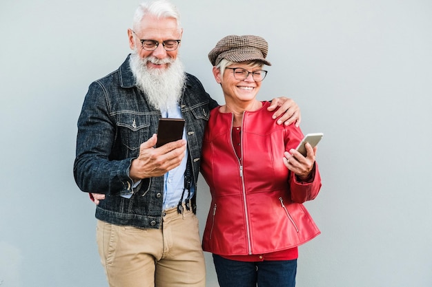 Foto senior koppel plezier met het gebruik van mobiele telefoons buiten focus op gezichten