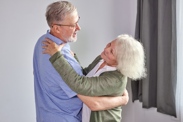 Senior koppel veel plezier dansen thuis, romantische volwassen grijsharige man en vrouw voelen energiek actief genieten familie pensioen weekend, vakantie samen doorbrengen